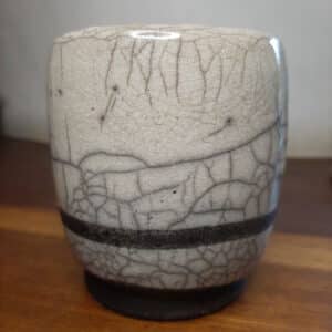 Mug noir et blanc cuit selon la technique du raku, ce qui lui confère quelques craquelures dans lesquelles ont pénétré les fumées.